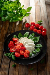 Wall Mural - Mozzarella with basil and cherry tomatoes on an old wooden table.