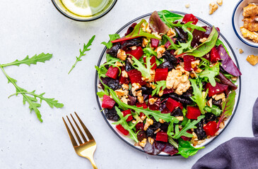 Wall Mural - Fresh crispy vegan salad with baked beetroot, dried prunes, arugula, chard and lnuts, white background