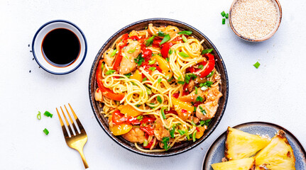 Wall Mural - Egg noodles with stir fried chicken, pineapple, paprika, green onion, ginger, garlic, soy sauce and sesame seeds. White background, top view