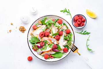 Wall Mural - Delicious summer salad with raspberries, chicken meat, fresh pears, ricotta cheese, red onion, nuts, spinach and arugula, white background, top view