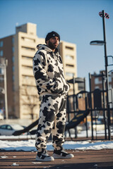 Sticker - A man in a cow print hoodie and sweatpants standing on a skateboard ramp