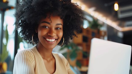 Wall Mural - A smiling woman is sitting at her desk with a laptop and looking into a camera