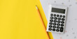 © chinnarach - close up top view on calculator with pencil and calendar on yellow background for money expense and debt management monthly concept