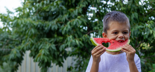 Wall Mural - boy eats watermelon on the background of nature. Selective focus