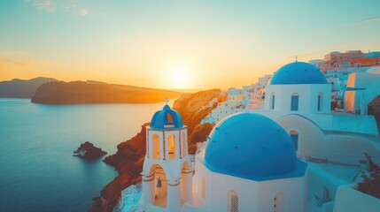 Wall Mural - Golden sunset illuminating white church with blue domes in oia, santorini, greece