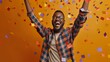 © Zainab - Ecstatic African American man celebrating success with arms raised and eyes closed under confetti rain on orange studio background. Excited male student won scholarship or got desired job vacancy