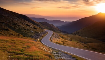 Wall Mural - winding road in the mountains at sunset stretching into the distance