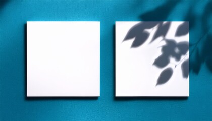 natural light casts shadows from the leaves of a tree on 2 square frames of white textured paper lying on a blue facture background mock up with an overlay of plant shadows