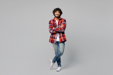 Full body young happy smiling confident Indian man he wears red shirt casual clothes look camera hold hands crossed folded isolated on plain grey color background studio portrait. Lifestyle concept.