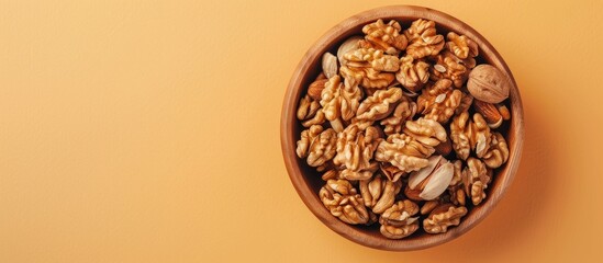 Aufkleber - Walnut kernel halves arranged attractively in a wooden bowl captured from above on a colored background focusing on healthy eating and super foods with copy space image