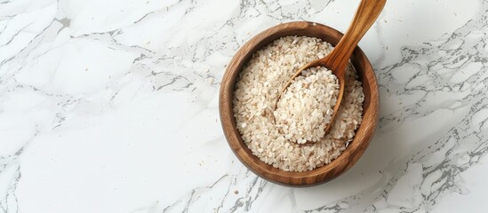 Aufkleber - Copy space image of a wooden bowl with a spoon filled with psyllium husk resting on a white marble table