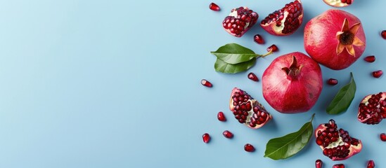 Poster - Copy space image featuring whole and cut pomegranate fruit on a light blue background in a square layout
