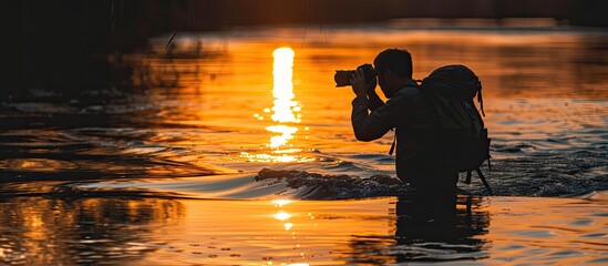 Poster - Photographer capturing photos in river at sunset shown in silhouette with serene copy space image