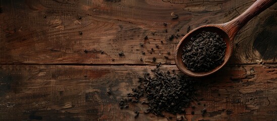 Poster - Wooden spoon holding dried black tea leaves displayed on a wooden table with copy space image available