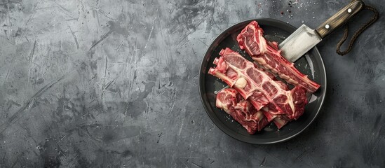 Poster - Fresh uncooked beef ribs presented in a bowl with a large knife on a grey background creating a visually appealing copy space image