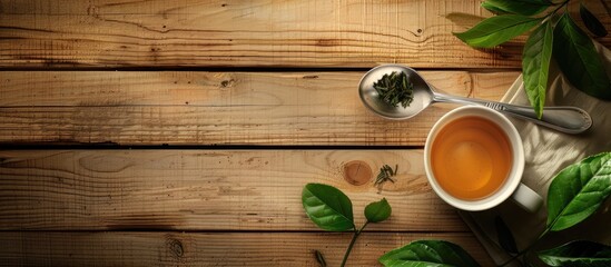 Poster - Wooden background with a cup filled with green tea leaves a spoon and ample copy space image