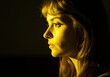 © IllustrationAlchemy - Closeup side portrait of a woman under a luminescent yellow light.