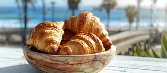 Croissants in a wooden bowl on a white wooden table with a seaside and pier setting Ideal for showcasing a continental breakfast with a copy space image