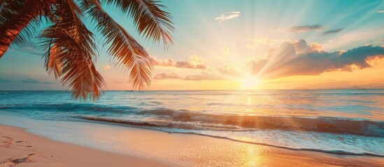 Wall Mural - A picturesque tropical beach at sunset with a beautiful golden sunset over the sea featuring a palm tree and blue sky ideal for holiday relaxation with a vintage photo aesthetic perfect for copy space