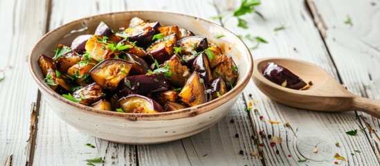 Poster - Studio photograph of a ceramic bowl with vegetable saute featuring eggplants set on a white wooden table with ample copy space for images