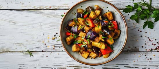Poster - Studio photograph of a ceramic bowl with vegetable saute featuring eggplants set on a white wooden table with ample copy space for images