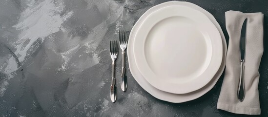 Poster - Minimalistic gray concept with a ceramic white plate cutlery and a napkin on a gray background ideal for text or image placement. copy space available