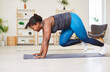 © Studio Romantic - Concentrated African American young woman doing intense workout in living room at home, performing mountain climber exercise in plank pose on exercise mat. Smiling woman training cardio indoors.