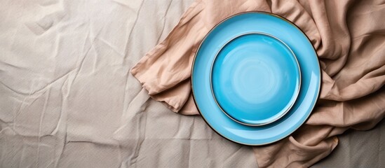 Poster - Bird s eye view of a blue plate on a tablecloth with a napkin offering a blank canvas for your design in the copy space image