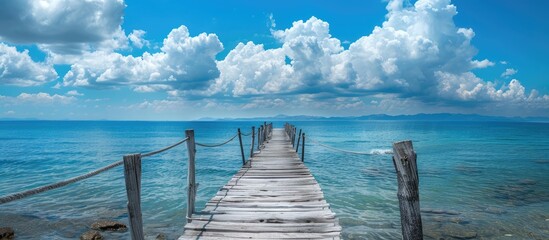 Poster - Aged wooden bridge over clear sea with appealing sky and attractive clouds in a pleasing copy space image
