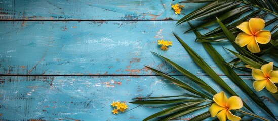 Poster - Copy space image of tropical palm leaf and yellow flowers on a blue wooden backdrop
