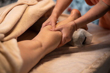 Wall Mural - Massage therapist with client. Massage for a healthy body. Hands of a masseur on a woman's body. Leg and foot massage