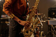 © pressmaster - Close-up of person playing saxophone, capturing the energy and focus during performance in recording studio setting with various musical instruments surrounding