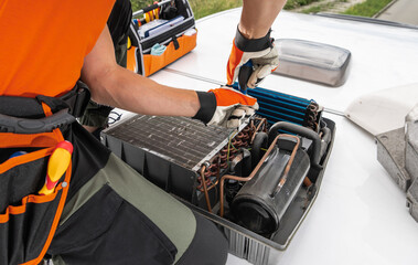 Technician Servicing RV Camper Rooftop HVAC Unit During Daytime in an Urban Setting