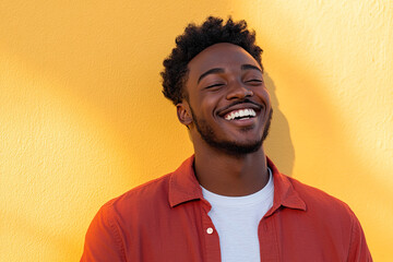 Bright and Cheerful Headshot of a Black Man Wearing a Red Shirt and White T-Shirt, Smiling on a Sunny Day with a Yellow Wall Behind