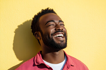 Bright and Cheerful Headshot of a Black Man Wearing a Red Shirt and White T-Shirt, Smiling on a Sunny Day with a Yellow Wall Behind