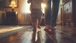© Iswanto - A baby takes its first steps while being held by a parent in a bright room.