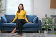 © Parichat - Young Woman Relaxing on a Blue Sofa in a Modern Living Room with Minimalist Decor and Indoor Plants