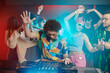 © pressmaster - Young ecstatic male deejay with raised arm mixing sounds on soundboard while making music for excited friends dancing in night club
