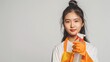 © Sirichat. Camphol - Happy young Asian woman housewife wearing rubber gloves and holding cleaning products, isolated on white background