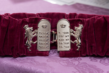 A red, felt Torah sash used for binding a Torah scroll, with a silver buckle embossed with the 10 commandments in Hebrew.