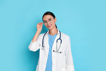 Wall Mural - Smiling nurse in uniform on light blue background