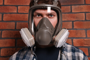 Wall Mural - Man in respirator mask near red brick wall