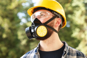 Wall Mural - Man in respirator mask and hard hat outdoors. Safety equipment