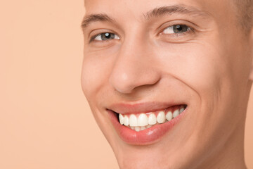 Canvas Print - Happy young man on beige background, closeup. Dental veneers