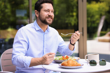 Canvas Print - Happy man having breakfast in outdoor cafe