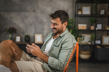 Portrait of happy adult man sit and use mobile phone