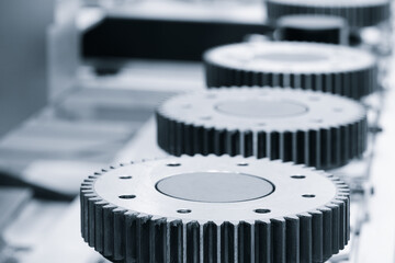 Poster - A row of metal gears are lined up on a white surface. The gears are all different sizes and shapes, but they all have a similar design. Concept of precision and order