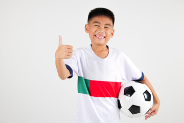 Portrait Asian smiling young boy kids wear uniform holding soccer ball and giving a thumbs up studio shot isolated white background, cute child playing football sport hobby for kids, leisure games