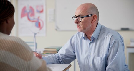 Aufkleber - Man, teacher and student at desk for education, question and help with information in classroom. Male tutor, person and discussion at table for shared knowledge, life science lesson and assistance