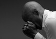 © herlanzer - man praying to god with hands together Caribbean man praying with black grey background with people stock image stock photo